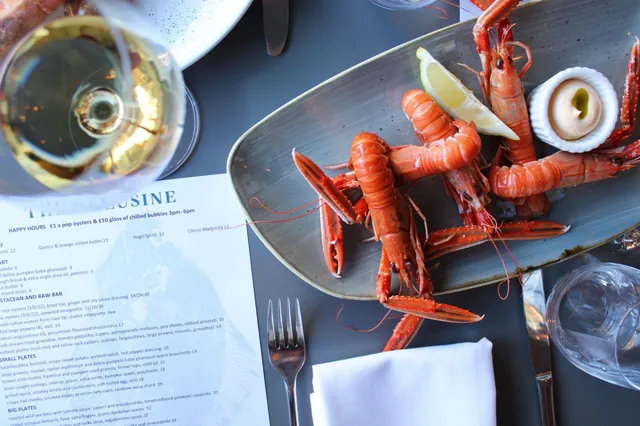 Langoustines with lemon beside a glass of white wine and the menu