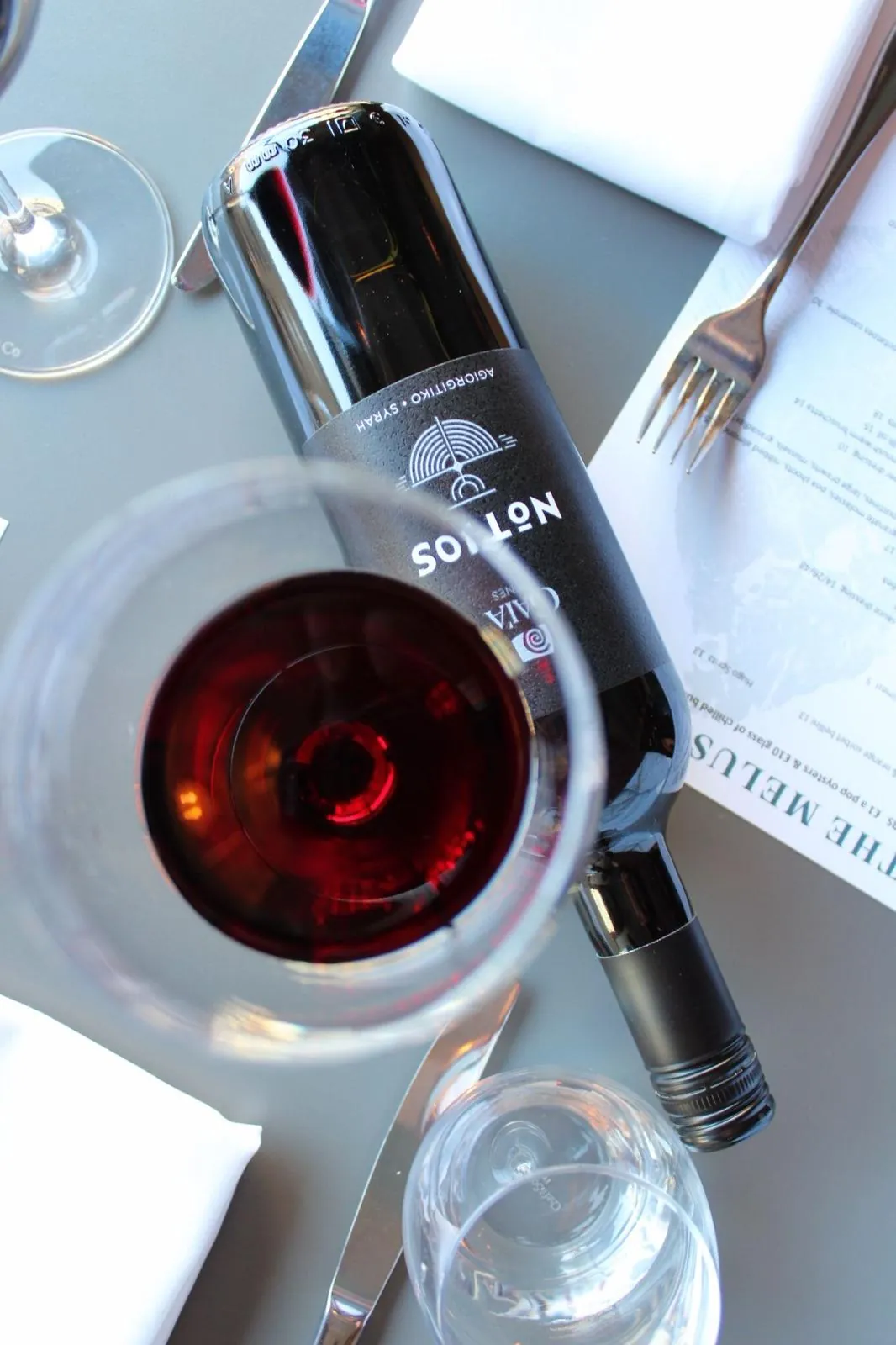 A glass of red wine and its bottle on a laid table