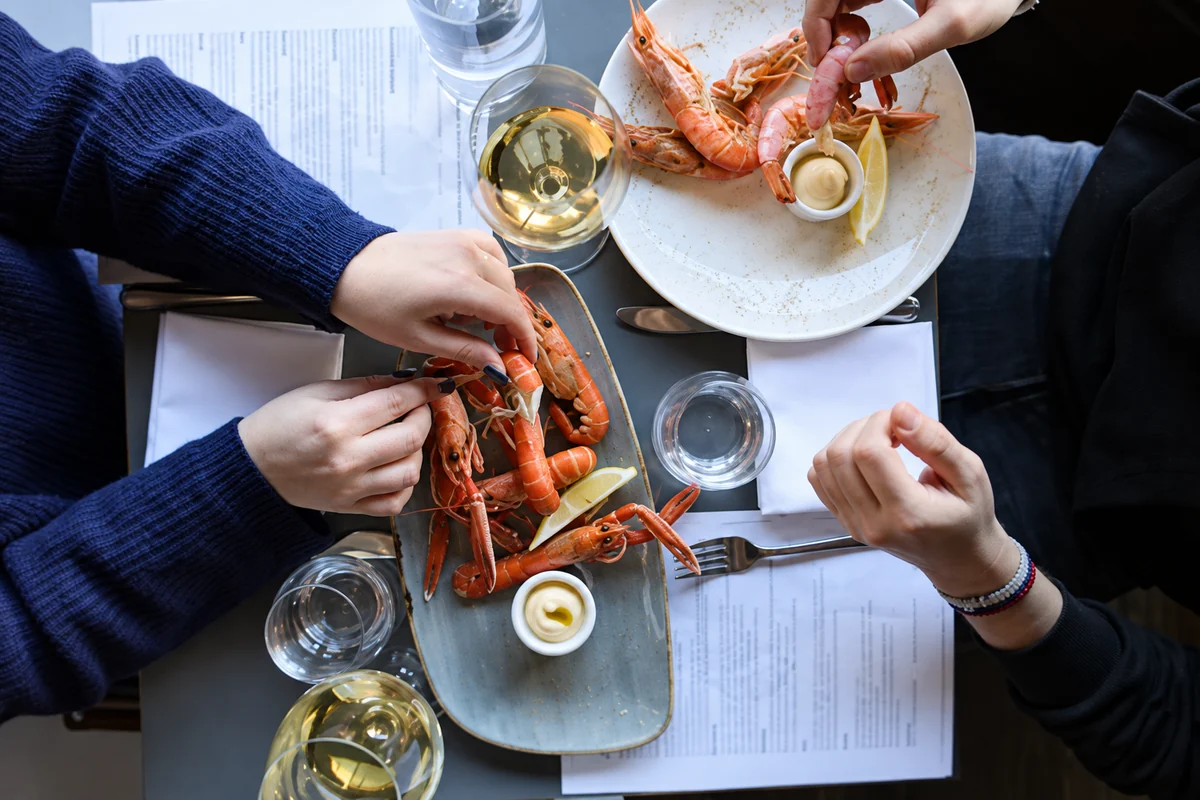 Guests sharing seafood plates and white wine around a table at The Melusine